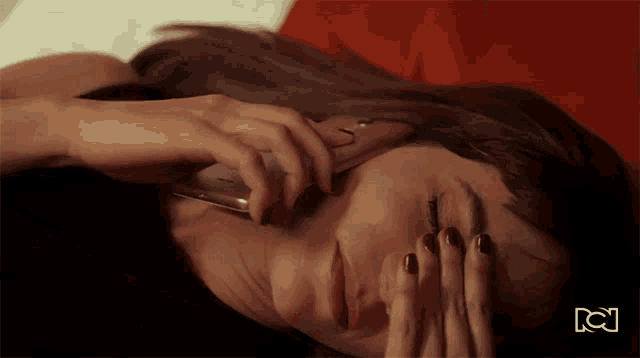 a woman laying on a bed talking on a cell phone with the letters kc on the bottom right