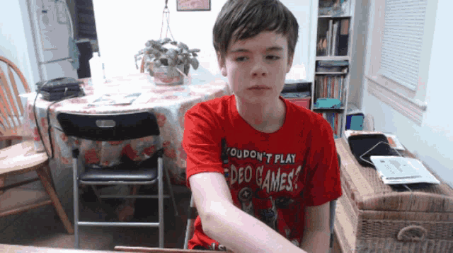 a young boy wearing a red shirt that says you don 't play video games