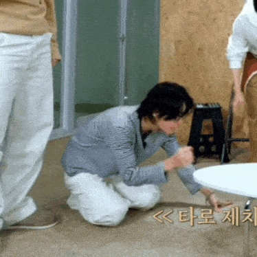 a man kneeling down next to a table with korean writing on the floor