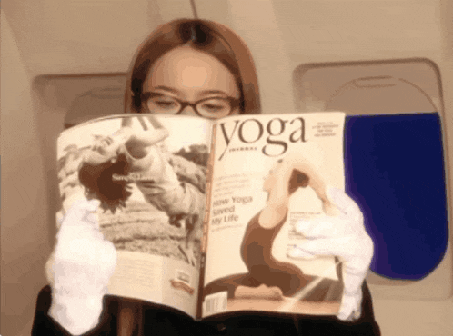 a woman is reading a yoga magazine on an airplane