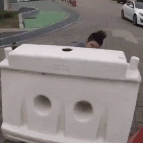 a woman is standing behind a white barrier on a street .
