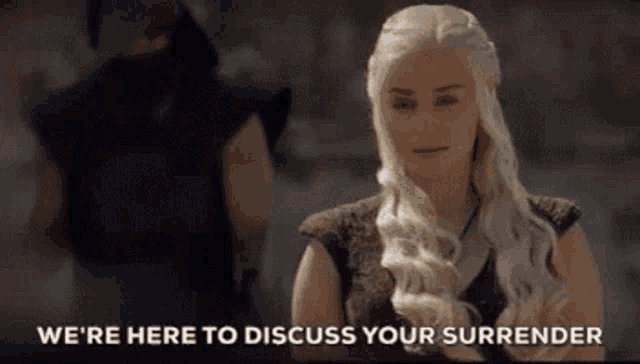 a woman with long blonde hair is standing in front of a man and says we 're here to discuss your surrender .