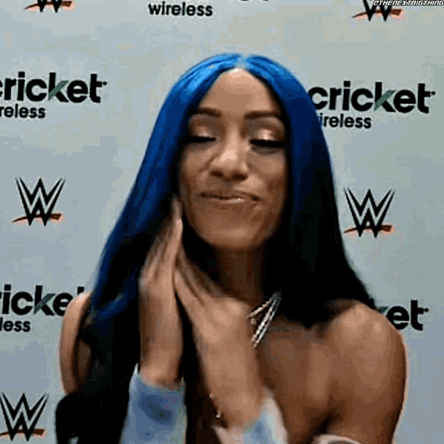 a woman with blue hair is standing in front of a wall that says cricket .