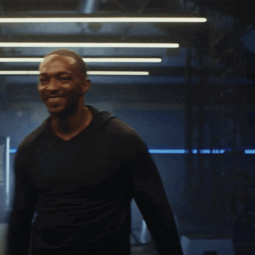 a man wearing a black shirt is smiling in a dark room