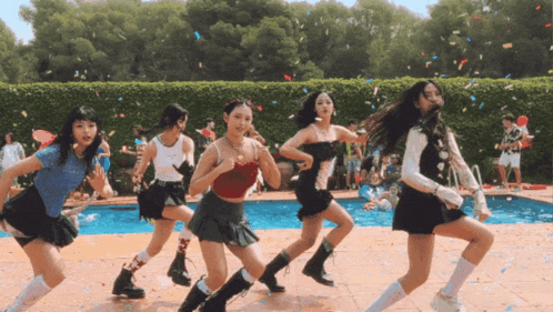 a group of young women are dancing in front of a swimming pool
