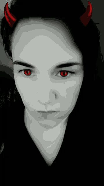 a black and white photo of a woman with red eyes and horns on her head