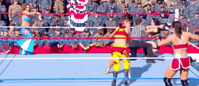 two women are wrestling in a ring with a referee in the background .