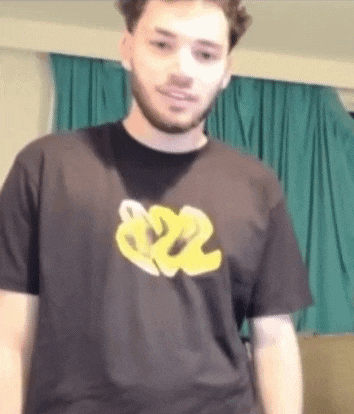 a man with a beard is wearing a black t-shirt with a yellow logo on the front .
