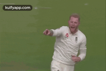 a man in a white shirt is smiling and dancing on a field .