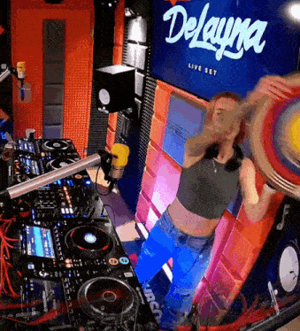 a woman playing a drum in front of a sign that says delayna