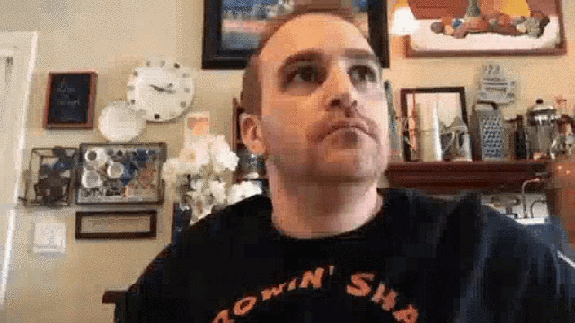 a man wearing a black shirt is sitting in a living room .