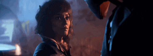 a man and woman are looking at each other in a dark room .