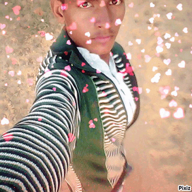 a man in a striped sweater takes a selfie with hearts falling from the sky