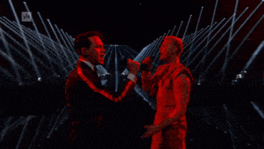 two men singing into microphones with yle written on the bottom left