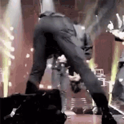 a man is dancing on a stage in front of a microphone and a crowd .