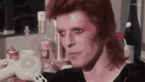 a close up of a man with red hair sitting in front of a mirror in a room .