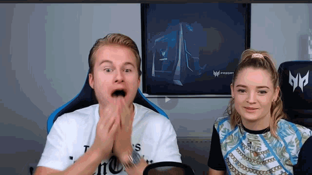 a man and a woman are sitting in front of a screen that says predator on it