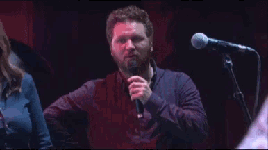 a man singing into a microphone while a woman watches