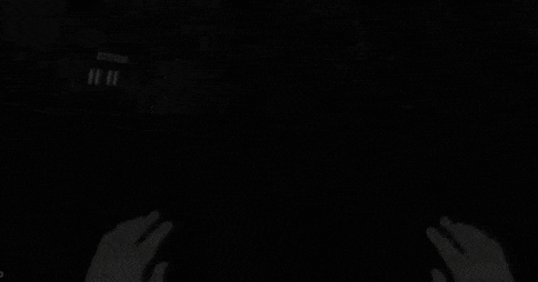 a person is playing a video game in a dark room with blood on their hands .