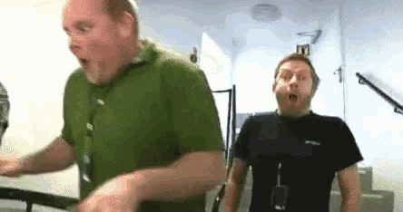 two men are standing next to each other in a room .