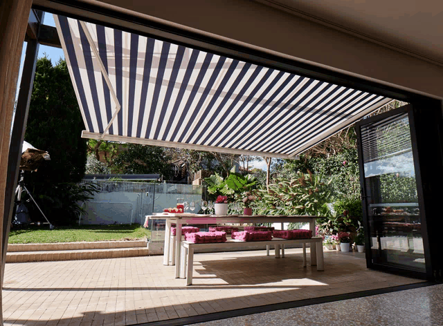 a blue and white striped awning is covering a patio with a table and benches