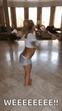 a woman in a crop top and shorts is dancing in a living room with the words weeeeeeeee !