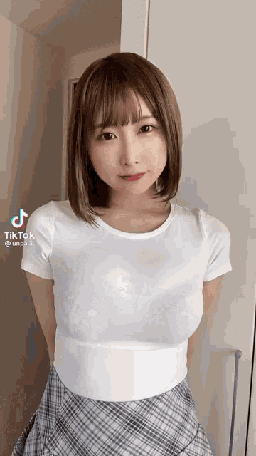 a woman wearing a white t-shirt and a plaid skirt has tiktok written on the bottom