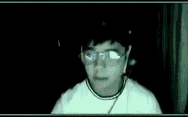 a man wearing glasses and a white shirt looks at the camera