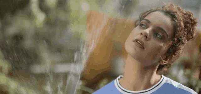 a woman with curly hair looks up at the sky
