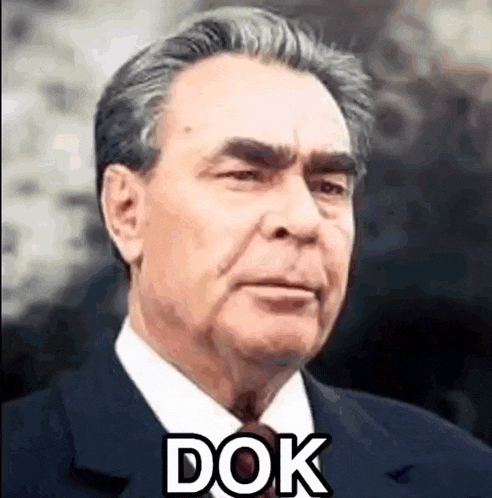 a man in a suit and tie is looking at the camera with the word dok written on his face .