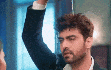 a man in a suit is standing in front of a window with water coming out of it .