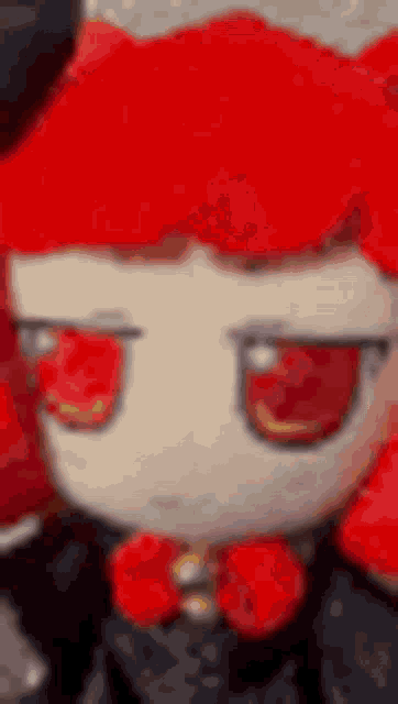 a stuffed animal with red hair and red eyes is wearing a black hat and a bow tie .