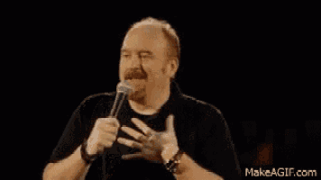 a man with a beard is holding a microphone in his hand and talking into it .
