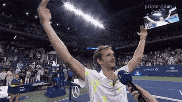 a tennis player is holding up his arms in the air while being interviewed by a reporter .