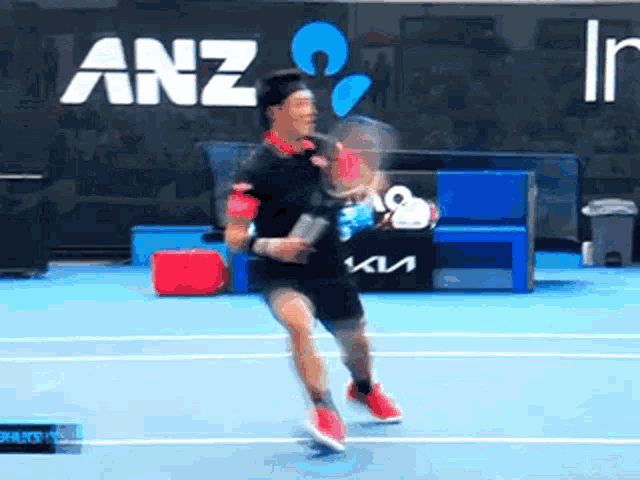a man is playing tennis on a court with anz written on the wall behind him