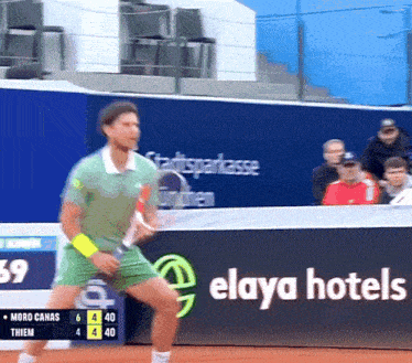 a man is playing tennis in front of a elaya hotels sign