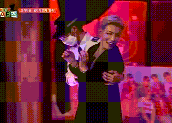 a man in a black suit is standing next to a woman in a black dress in front of a red background .