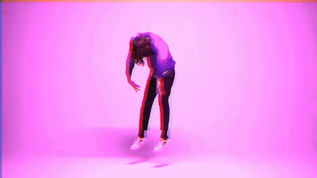 a man in a pink shirt is dancing on a pink background .