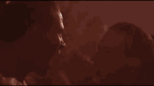 a man and woman are kissing in a dark room in a movie .