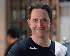 a man wearing a black shirt with the word perfect written on it is smiling .