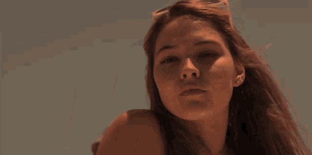 a woman wearing sunglasses covers her eyes with her finger