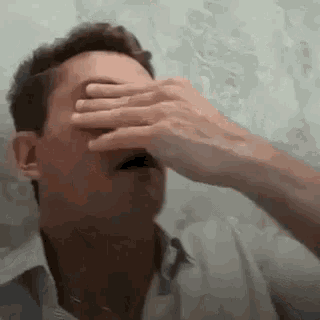 a man is covering his face with his hand .