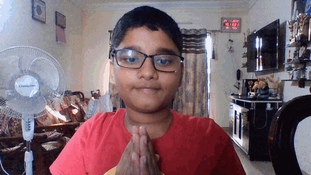 a boy wearing glasses and a red shirt stands in front of a fan that says cooling fan