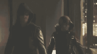 a man in a hooded jacket and a woman in a red mask are walking down a street .