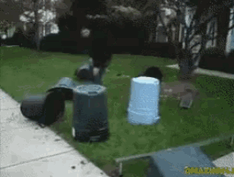 a person is standing on a sidewalk surrounded by trash cans and buckets ..