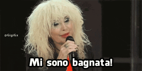 a woman with blonde hair is singing into a microphone and says mi sono bagnata .