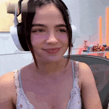 a woman wearing headphones and a bra smiles while sitting in a chair