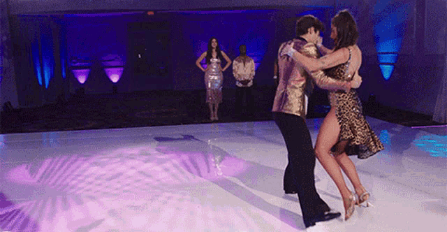 a man and a woman are dancing on a white floor