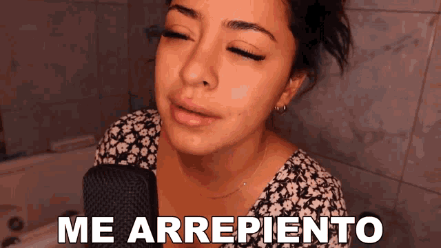 a woman singing into a microphone with the words me arrepiento written above her