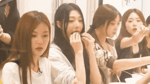 a group of girls are sitting around a table eating food